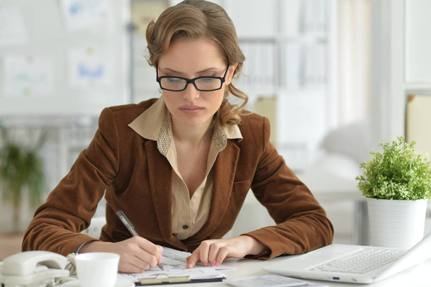 Portrait of  young businesswoman in eyeglasses  working with laptop - Fotó, kép