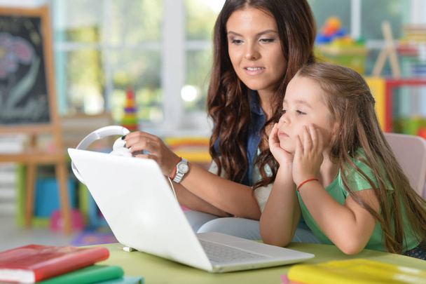 portrait of happy  mother and daughter using laptop at playroom - Fotó, kép