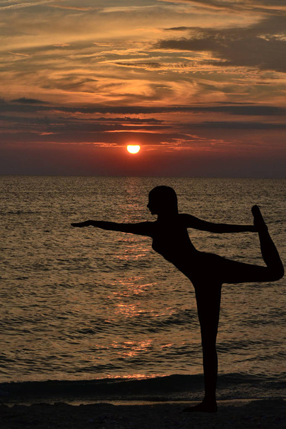 Warrior pose from yoga by woman silhouette on sunrise - Photo, Image
