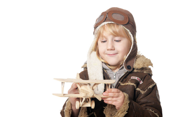 cute little boy aviator wit wooden plane toy  - 写真・画像