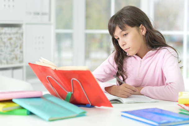happy schoolgirl sitting at desk and  studying. Education  - Valokuva, kuva