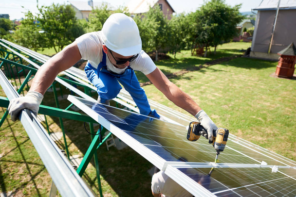 Profesyonel çalışan güneş panelleri yeşil metal konstrüksiyon üzerinde yükleme miğfer farklı cihazlar kullanılıyor.  - Fotoğraf, Görsel