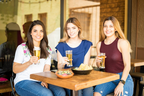 Kolmen hyvännäköisen naisystävän muotokuva juomassa olutta ravintolassa
 - Valokuva, kuva