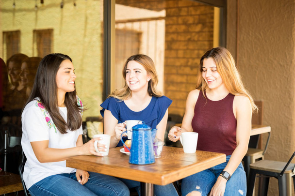 Tres jóvenes riendo en el restaurante con café
 - Foto, Imagen