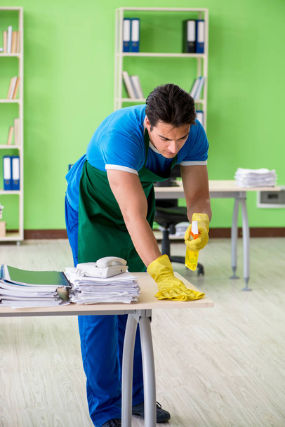 Мужчина красивый профессиональный уборщик работает в офисе - Фото, изображение