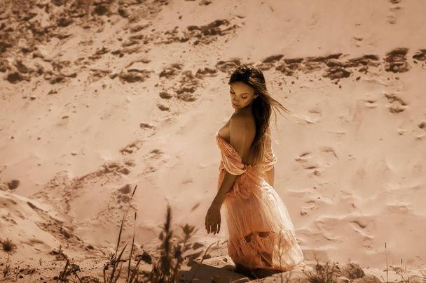 glamour brunette lady sits on a sand in a desert - Fotoğraf, Görsel