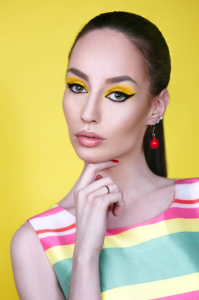 Close view of woman with bright makeup on yellow background - 写真・画像