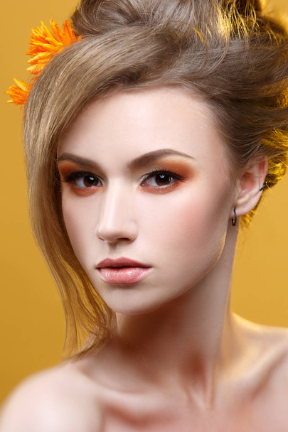 Fashion beauty portrait of girl with orange makeup on yellow background. - Foto, Imagen