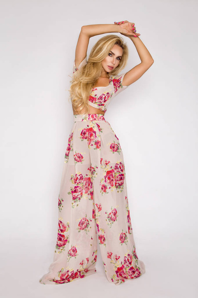 Krásná, sexy, elegantní žena s blond vlasy pózy v ateliéru v elegantních šatech s květinami a klobouk. - Fotografie, Obrázek