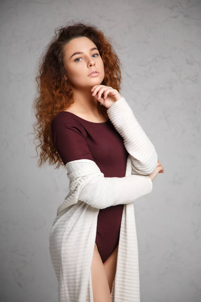 Portrait of red-haired girl in a cardigan and body on gray background. - Photo, Image