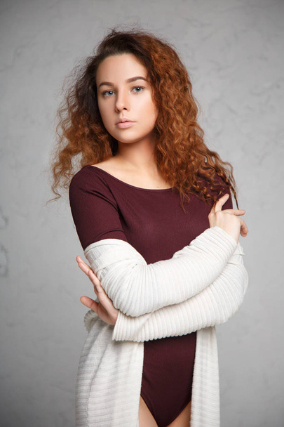 Portrait of red-haired girl in a cardigan and body on gray background. - 写真・画像