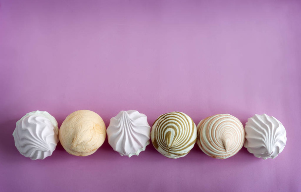 Marshmallows of different varieties are presented in one line on a pink background. The view from the top. - Fotografie, Obrázek