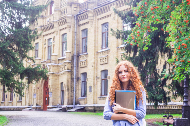 A vörös hajú lány hallgató mappák és oktatási anyagok, kezében az Egyetem mellett. Vissza ehhez: iskola fogalmát. diákélet - Fotó, kép