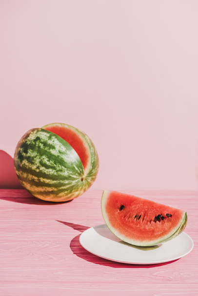 Close-up van segment van watermeloen op plaat op roze achtergrond - Foto, afbeelding