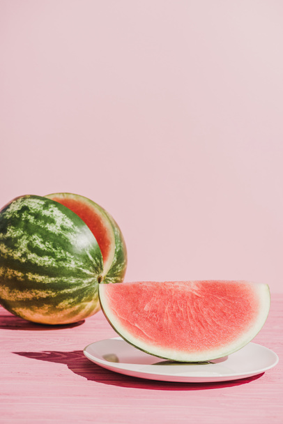 close up view of slice of watermelon on plate on pink background - Фото, зображення