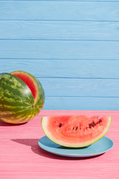 close up view of fresh watermelon on pink tabletop on blue backdrop - Foto, Bild