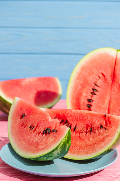 close up view of juicy watermelon slices on plate on blue backdrop - Fotografie, Obrázek