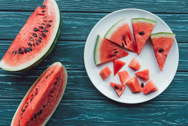 flat lay with fresh watermelon pieces on plate on blue wooden tabletop - Photo, image
