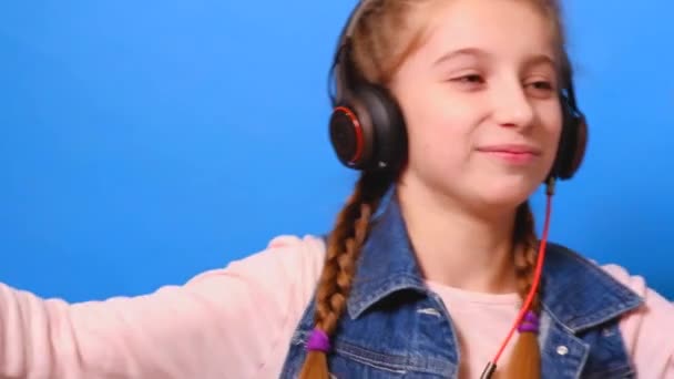 A little girl in headphones, dancing and enjoys the music - Imágenes, Vídeo