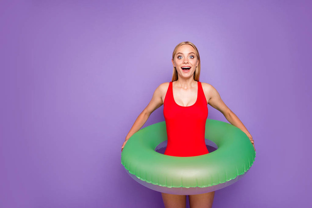 Water is so warm! Photo portrait of charming joyful rejoicing cute lovely girl holding lifebuoy on waist in hands looking at camera isolated on violet background copy space - Photo, Image