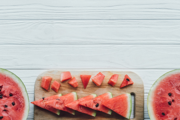 flat lay with arranged watermelon pieces on cutting board on wooden tabletop - Zdjęcie, obraz