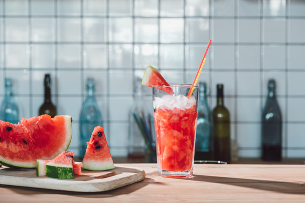 Close-up van watermeloen drankje in het glas en stukken van de verse watermeloen op snijplank in café - Foto, afbeelding