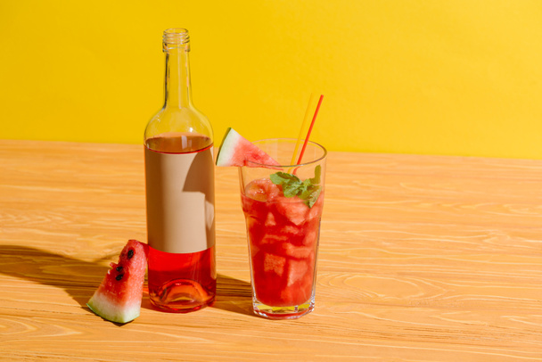 lähikuva tuoreen vesimelonin ja vesimelonin juomasta puupinnalla keltaisella pohjalla
 - Valokuva, kuva
