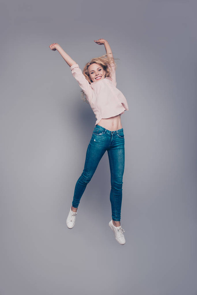 Full body length size vertical of attractive beautiful curly-haired blonde caucasian young girl wearing casual flying in air. Isolated over grey background - 写真・画像