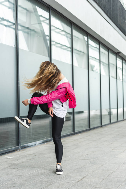 young stylish woman with obscured face by hair dancing at urban street - 写真・画像