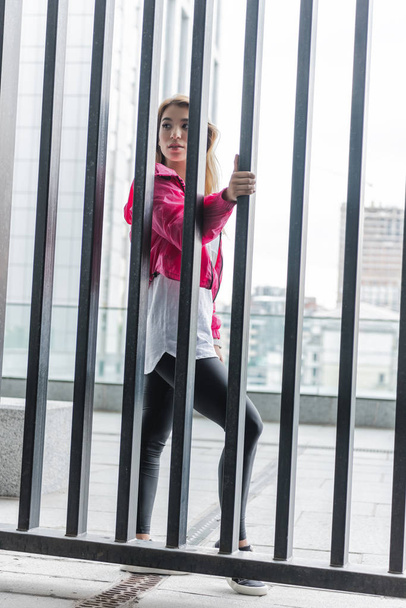 Metal çit duran ve uzak kentsel Caddesi'nde seyir genç şık Asyalı kadın - Fotoğraf, Görsel