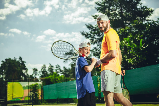 Happy male and boy playing tennis - Фото, изображение