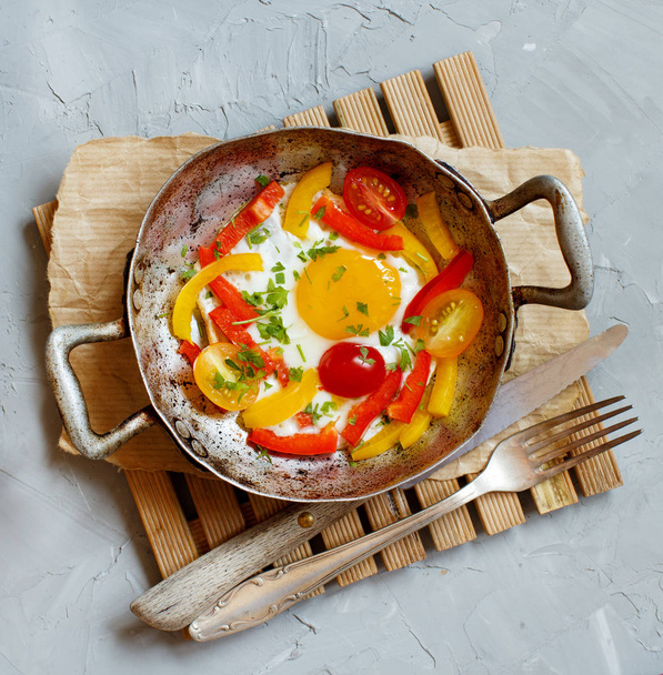 Gebakken ei met een paprika en tomaten op een oude koekenpan  - Foto, afbeelding