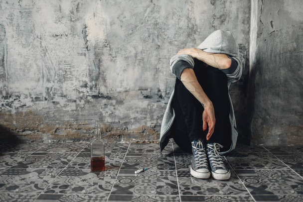 Drogadicto deprimido sentado en el suelo, síntoma de abstinencia. Concepto de adicción a las drogas, drogadictos
 - Foto, Imagen