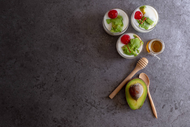 Szemüveg, cseresznye és avokádó szeletelt joghurt kő háttér - Fotó, kép