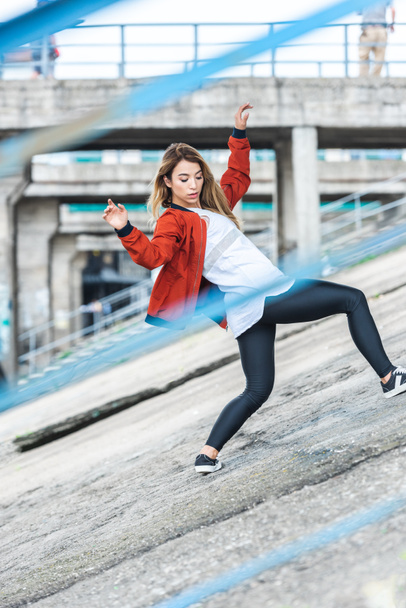 selective focus of young asian stylish female urban dancer dancing at city street - 写真・画像