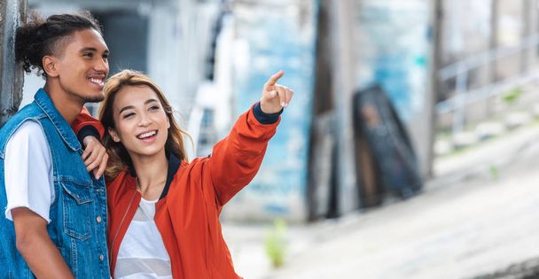 избирательный фокус улыбающейся азиатской женщины, указывающей пальцем на смешанного расового бойфренда на городской улице
  - Фото, изображение