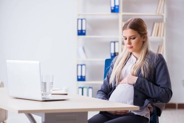 Pregnant woman employee in the office - 写真・画像