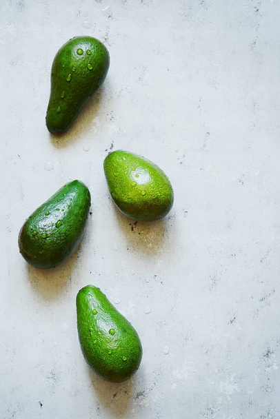 Rijpe hele groene avocado op een grijze achtergrond. Flat lag. Voedsel concept. Bovenaanzicht. Groene Brazilië patroon in minimalistische plat lag stijl, kopie ruimte - Foto, afbeelding