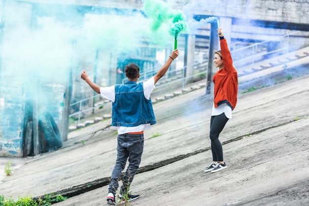 feliz pareja sosteniendo coloridas bombas de humo en la calle de la ciudad
 - Foto, imagen