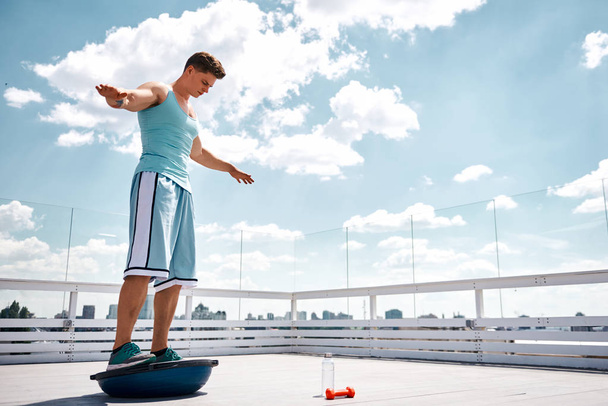 Sportowiec jest równoważenie na Bosu piłkę na dachu - Zdjęcie, obraz