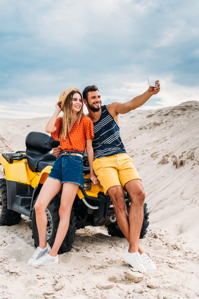 sorridente giovane coppia con ATV prendere selfie nel deserto
 - Foto, immagini