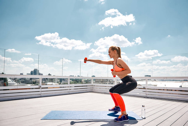 Smiling woman is exercising with outfit on high terrace - Photo, image