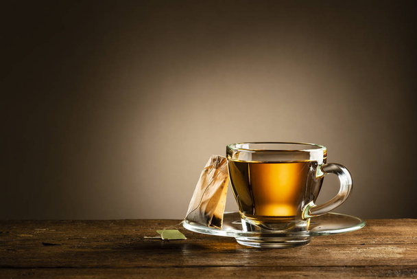 glass cup of tea with tea bag on wooden table - Photo, Image