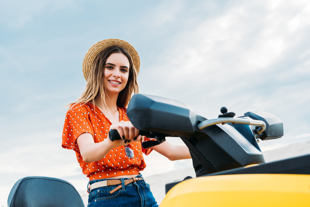 beautiful young woman sitting on all-terrain vehicle and looking at camera - Photo, Image