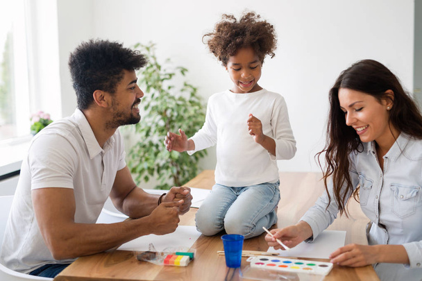Mom and dad drawing with their daughter at home - Фото, изображение