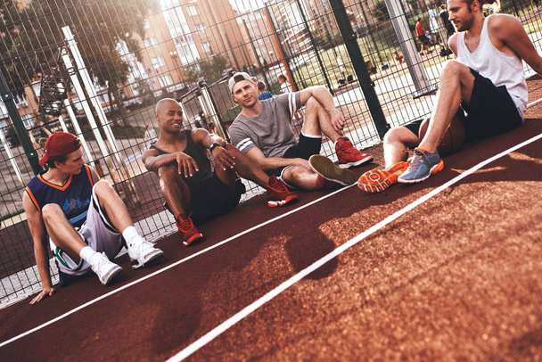 group of young sportsmen sitting on basketball court - Foto, Imagen
