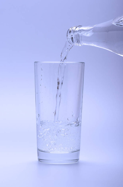 Mineral cold water pouring into the glass from the bottle - Foto, Imagen