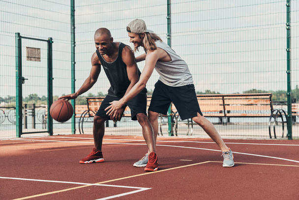 two sportsmen playing basketball outdoors on basketball arena court - Foto, afbeelding
