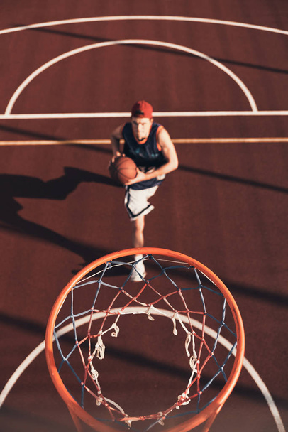 sportsman preparing to score slam dunk while playing basketball outdoors  - Fotografie, Obrázek
