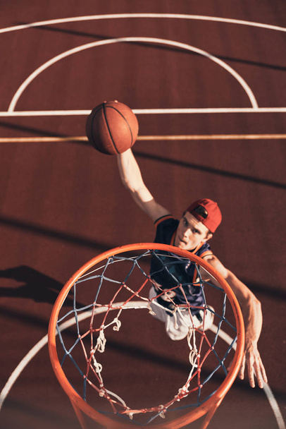 Best basketball player scoring slam dunk while playing basketball outdoors - Foto, afbeelding